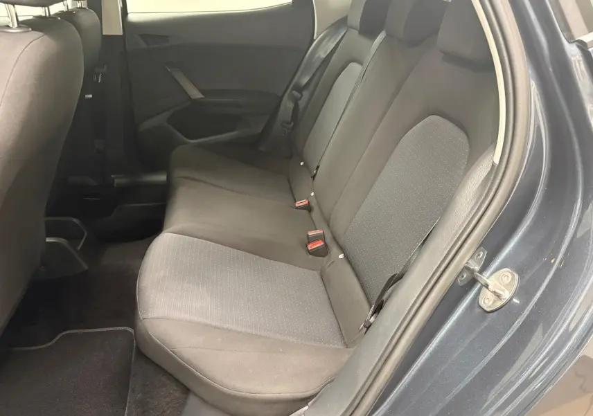Vue intérieure côté droit sur les sièges arrière en tissu gris d’une SEAT Ibiza 2024 gris magnétique, porte ouverte.