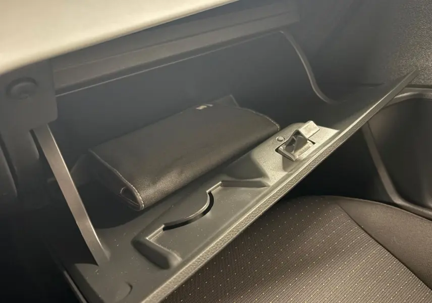 Vue rapprochée de la boîte à gants ouverte du SEAT Ibiza gris magnétique, avec un étui noir à l'intérieur.
