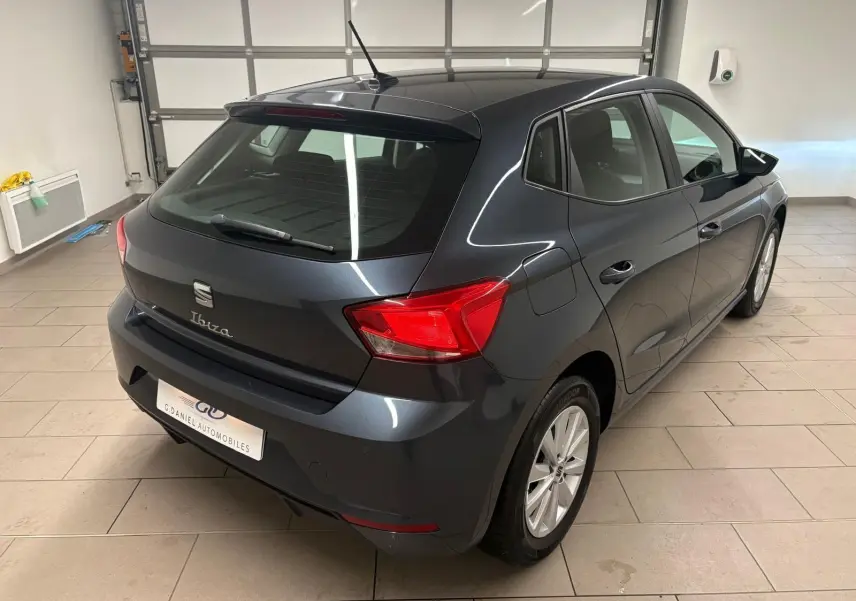 SEAT Ibiza 2024 gris magnétique vue 3/4 arrière droit dans un garage avec feux arrière rouges visibles.