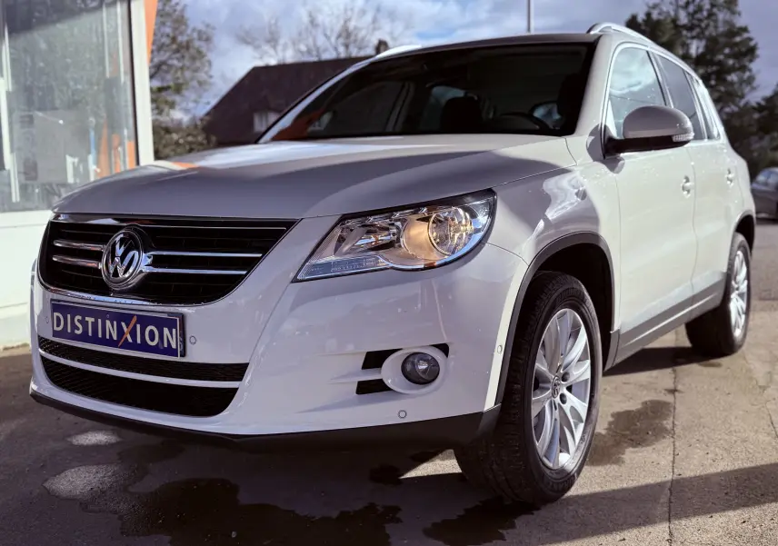 Volkswagen Tiguan blanc vu de 3/4 avant droit avec phares allumés et jantes alliage 17 pouces.