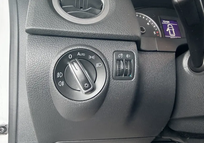 Gros plan sur le bouton de commande des phares à gauche du tableau de bord d’un Volkswagen Tiguan blanc de 2010.