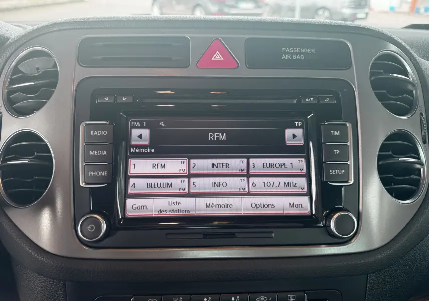 Vue frontale du tableau de bord du Volkswagen Tiguan 2010, avec écran radio tactile et aérateurs ronds noirs.