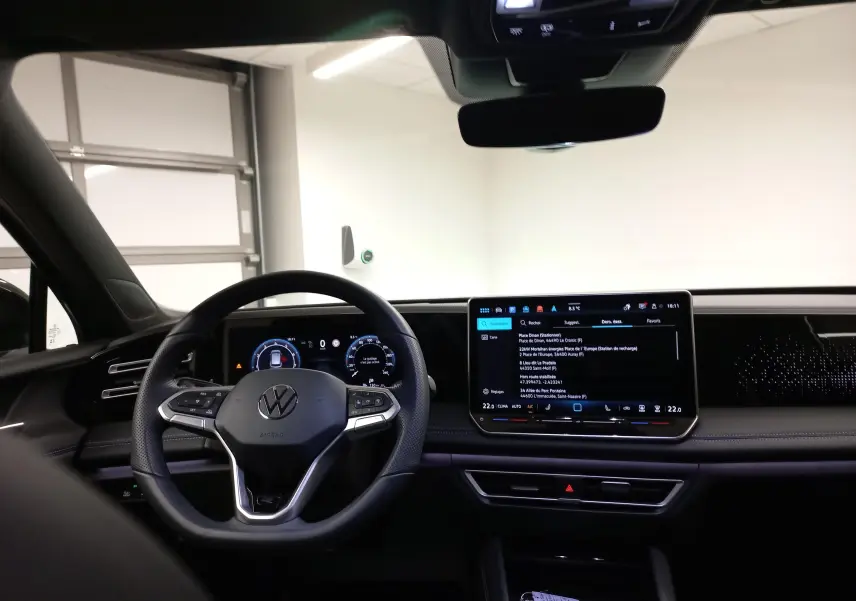 Vue intérieure du tableau de bord du Volkswagen Tiguan 2025, avec volant multifonction et écran tactile central lumineux.
