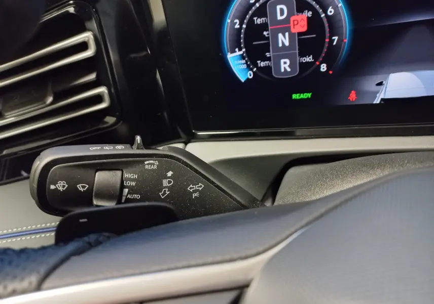 Gros plan sur la commande des clignotants et essuie-glaces du Volkswagen Tiguan 2025, tableau de bord numérique en arrière-plan.