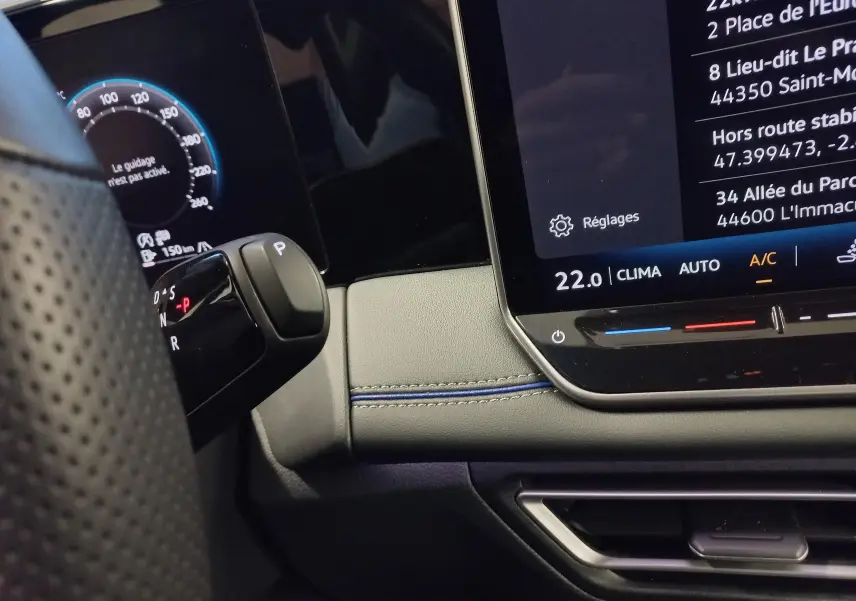 Gros plan sur la console centrale et levier de vitesses du Volkswagen Tiguan 1.5 eTSI 150ch DSG7, intérieur noir avec surpiqûres bleues.