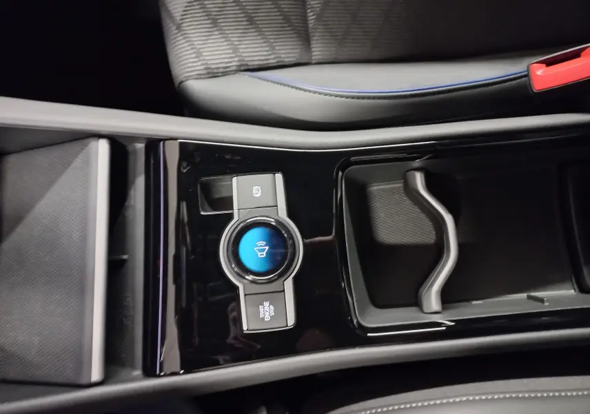 Gros plan sur la console centrale noire du Volkswagen Tiguan 2025 avec bouton Start/Stop et rangement adjacent.