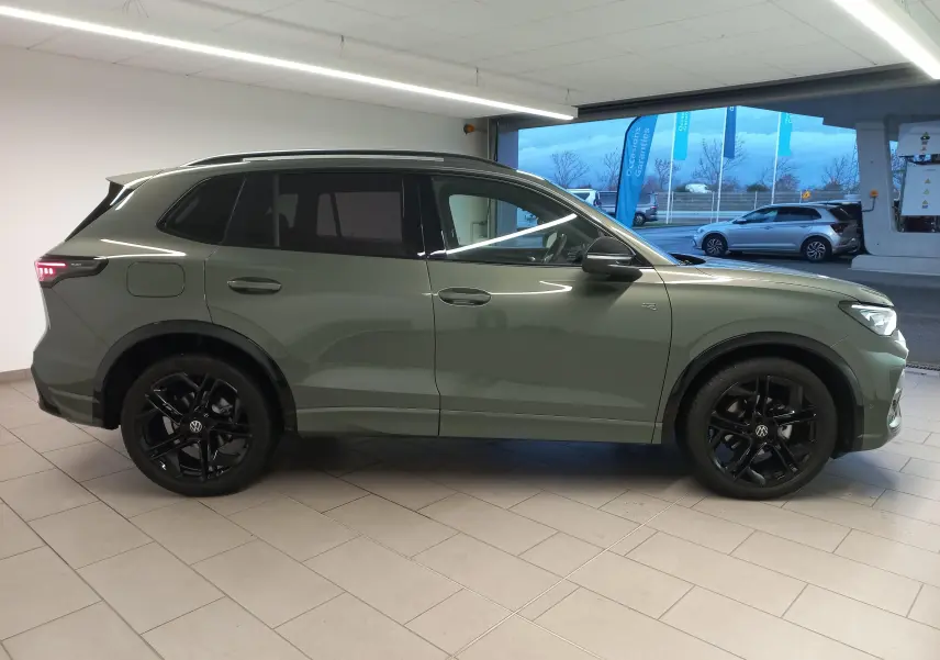 Vue de profil côté gauche d'un Volkswagen Tiguan 2025 vert Cipressino avec jantes noires et vitres surteintées.