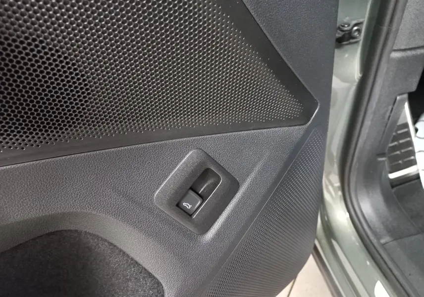 Détail du bouton d'ouverture du coffre sur la porte arrière côté gauche du Volkswagen Tiguan Vert Cipressino 2025.