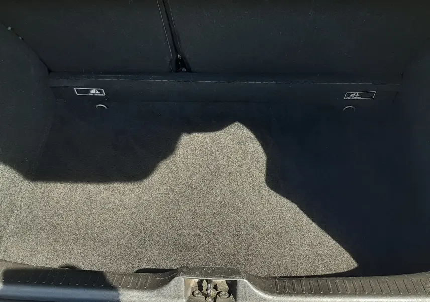 Coffre ouvert de Renault Clio IV gris titanium, vue plongeante montrant l'espace de chargement vide et la moquette noire.