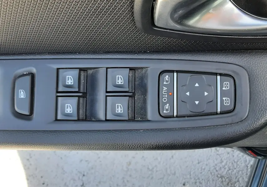 Gros plan sur la commande des vitres électriques et réglages des rétroviseurs côté conducteur d'une Renault Clio IV gris titanium.