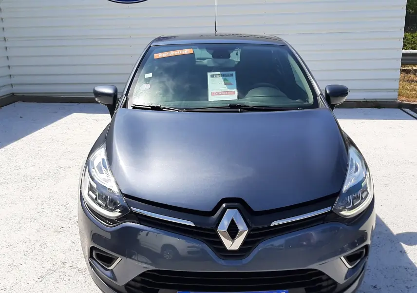 Vue frontale d'une Renault Clio IV gris titanium, avec logo Renault bien visible et panneau "OCCASION" sur le pare-chocs.