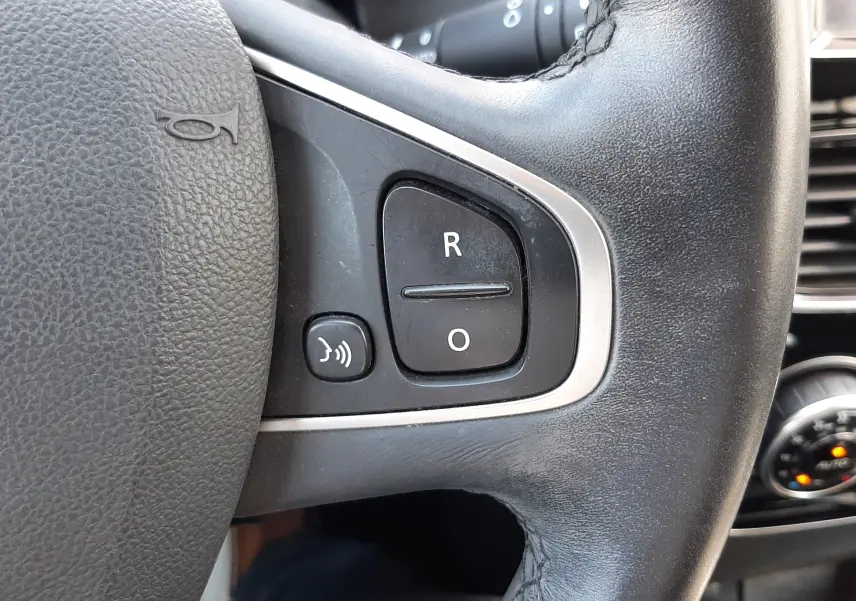 Gros plan sur le volant en cuir noir de la Renault Clio IV 0.9 TCE 90 Intens, avec boutons de commande intégrés.