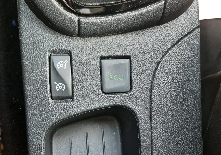 Gros plan sur les commandes de mode ECO et régulateur de vitesse, console centrale noire d'une Renault Clio IV gris titanium.