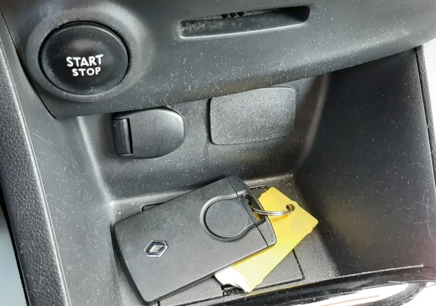 Gros plan sur la console centrale d'une Renault Clio IV gris titanium avec clé et bouton start/stop visible.