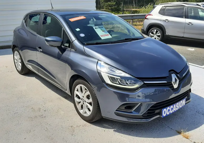 Renault Clio IV gris titanium vue 3/4 avant droit, compacte avec phares LED et jantes alliage 16 pouces.