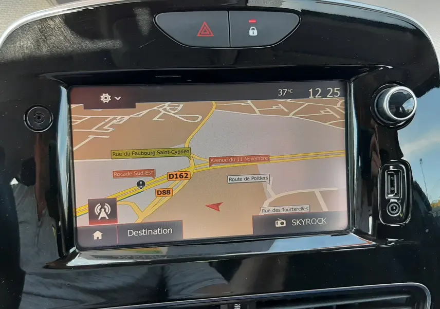 Vue rapprochée de l’écran tactile du GPS intégré dans une Renault Clio IV gris titanium, avec commandes et ports USB visibles.