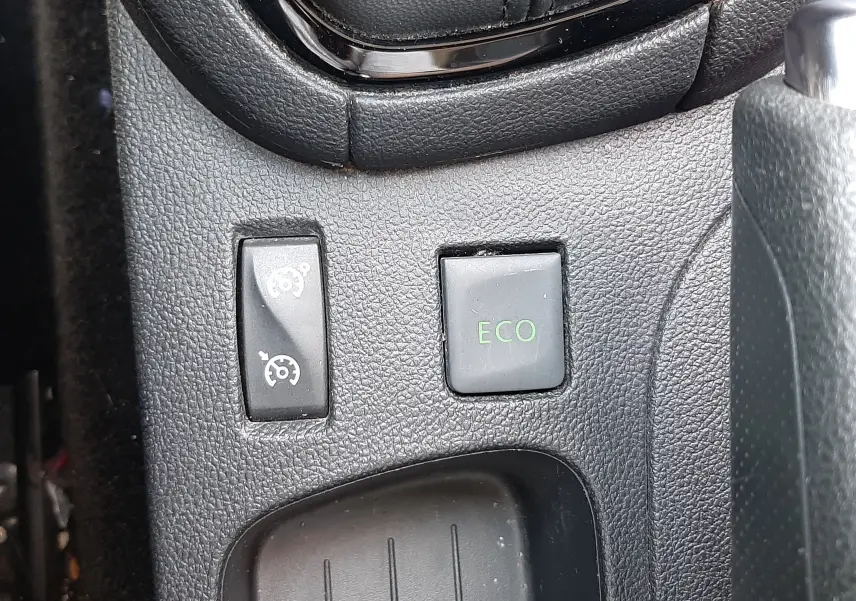 Gros plan sur les commandes ECO et régulateur de vitesse près du levier de vitesses d'une Renault Clio IV gris titanium.