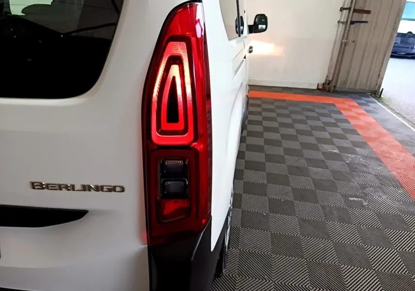 Gros plan sur le feu arrière droit rouge d’un Citroën Berlingo blanc, vue arrière côté droit dans un garage.