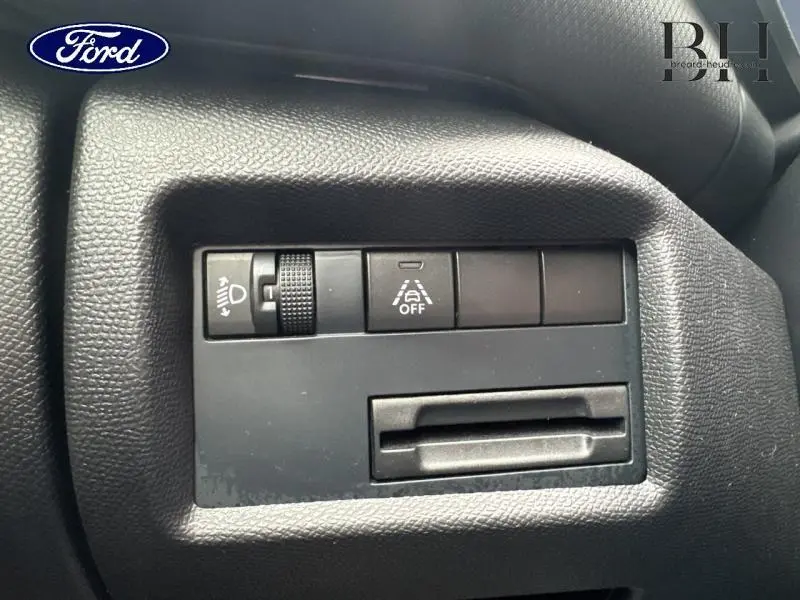 Détail des commandes de réglage des phares et de l'aide à la conduite sur tableau de bord noir d'une Citroën C5 Aircross gris acier.