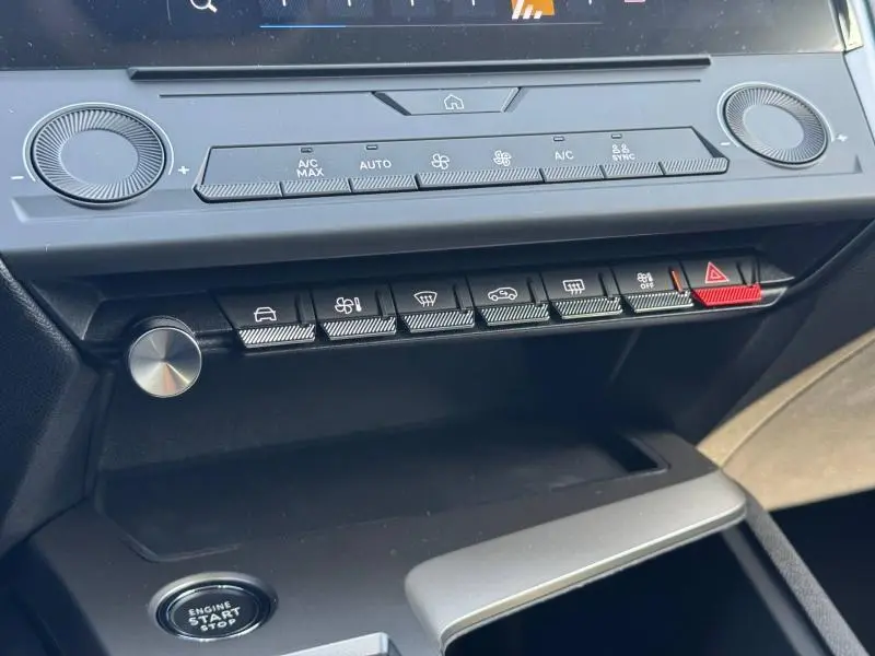 Vue rapprochée de la console centrale de la Peugeot 308 2025, boutons de climatisation et démarrage sans clé visibles.