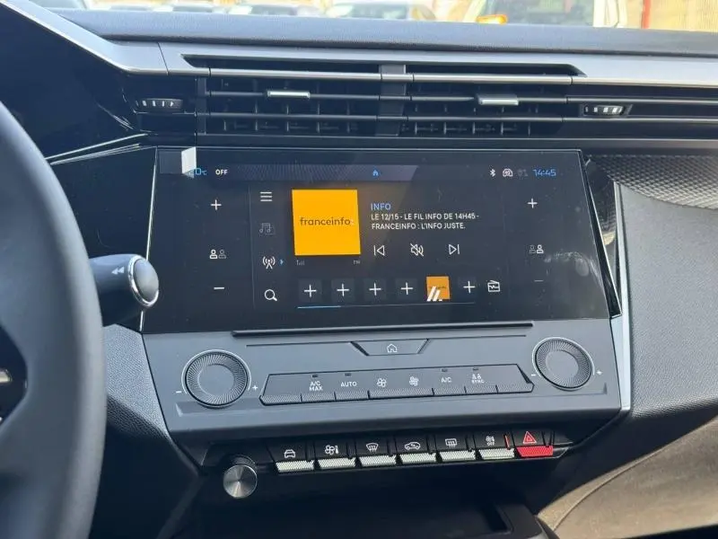 Vue rapprochée de l’écran tactile central et des commandes de climatisation dans l’habitacle de la Peugeot 308 blanche.