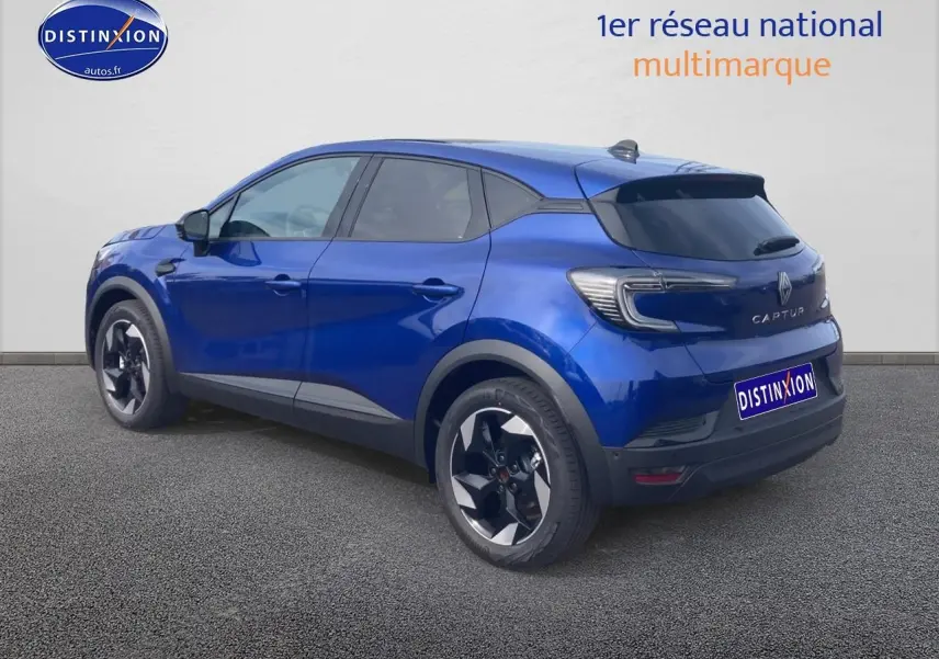 Renault Captur bleu iron vu en 3/4 arrière droit, avec jantes alu et feux arrière LED distinctifs.