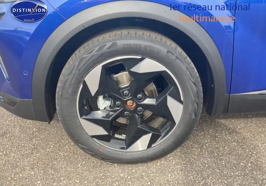 Gros plan sur la roue avant gauche d’un Renault Captur bleu iron avec jante alliage noire et grise.