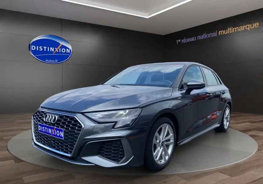 Audi A3 30 TFSI S Line gris foncé vue 3/4 avant dans un showroom avec éclairage intérieur.