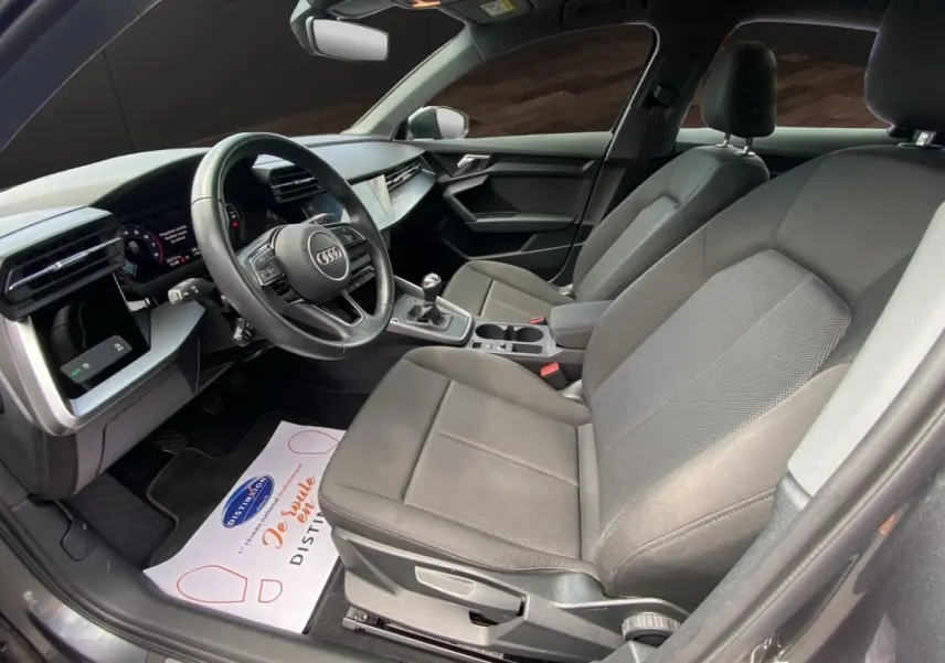 Vue intérieure côté conducteur de l’Audi A3 30 TFSI S Line 2021 gris foncé, volant cuir et console centrale avec boîte manuelle.