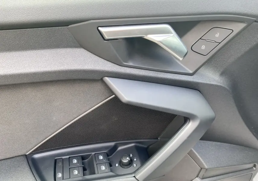 Détail de la porte côté conducteur de l'Audi A3 30 TFSI S Line 2021 gris foncé, avec commandes électriques et poignée argentée.