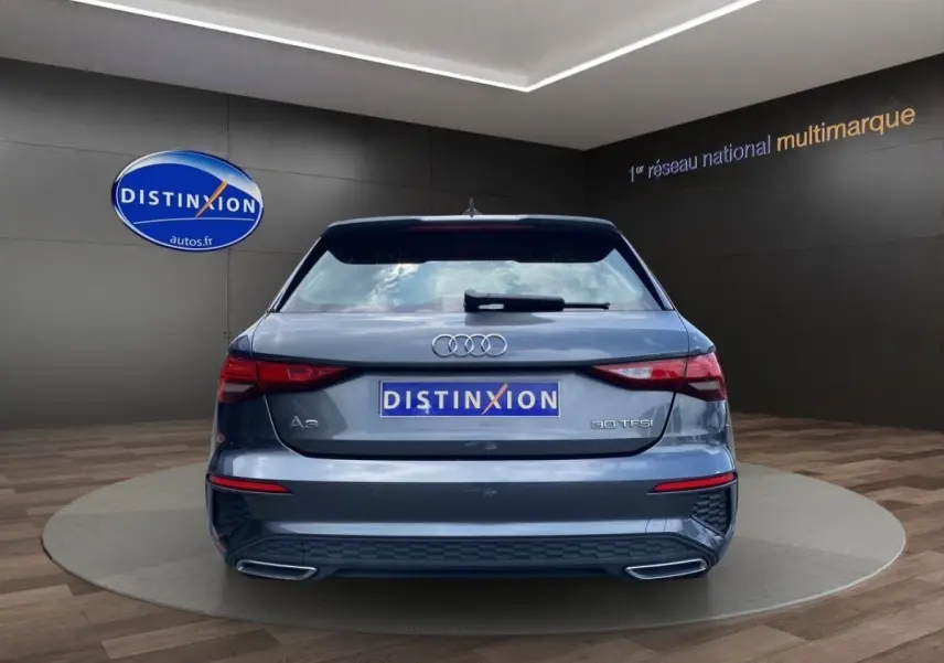 Vue arrière d'une Audi A3 30 TFSI gris foncé avec double sortie d'échappement et logo distinctif sur coffre.
