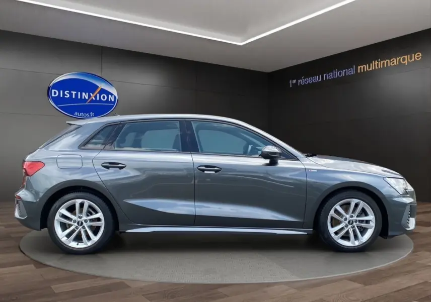 Audi A3 30 TFSI S Line gris foncé vue de profil côté gauche en intérieur showroom avec jantes alliage.