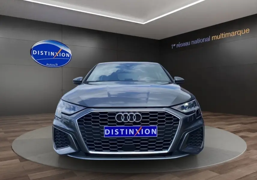 Vue frontale d'une Audi A3 30 TFSI S Line gris foncé avec calandre hexagonale et phares LED allumés.