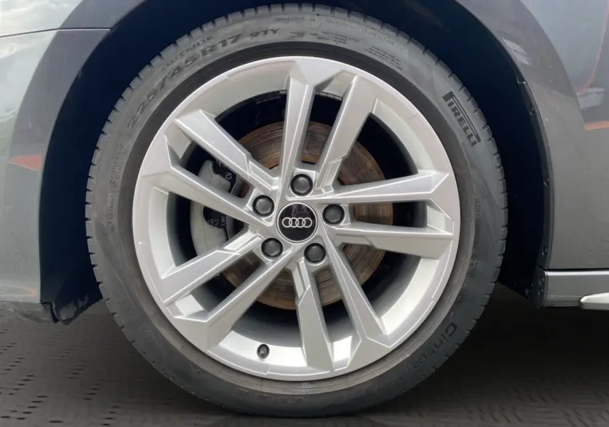 Gros plan sur la roue avant droite d'une Audi A3 gris foncé, jante alliage à design moderne en étoile.