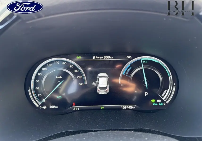 Image d'un tableau de bord numérique d'une Kia Xceed noire, affichant la vitesse, l'autonomie et l'état hybride rechargeable.
