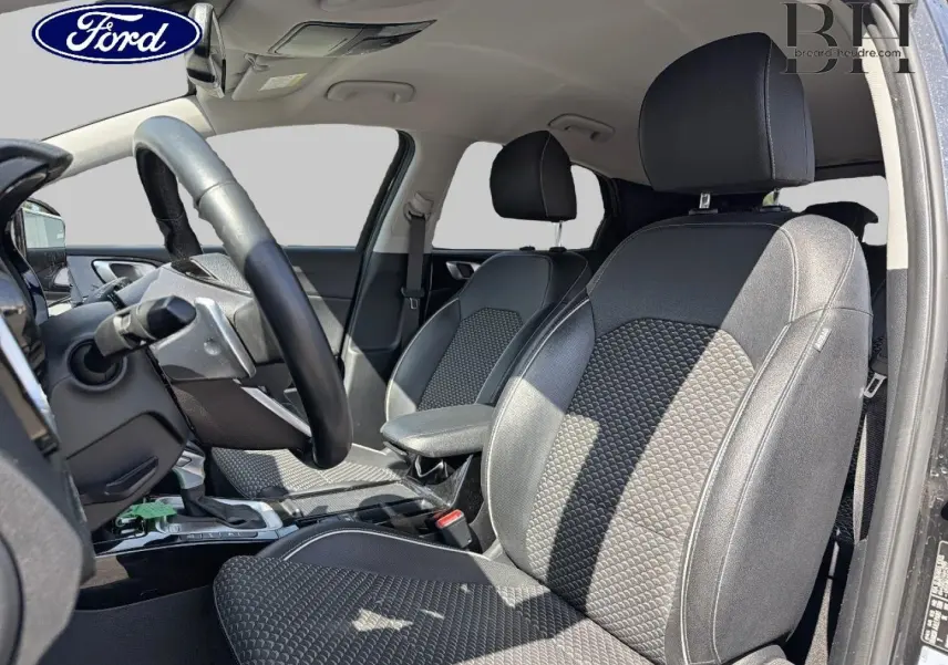 Intérieur avant du KIA Xceed 2022, vue côté conducteur, sièges en tissu noir avec motifs texturés et volant cuir.