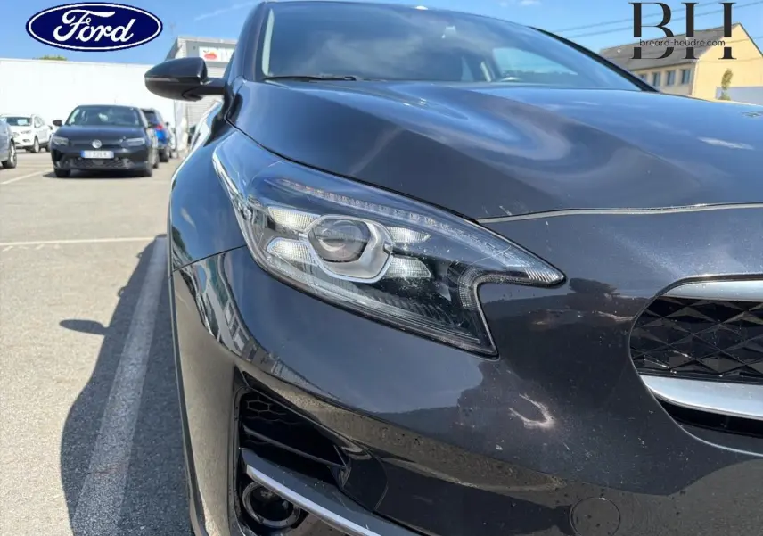 Gros plan sur l'avant gauche du KIA Xceed noir Basalte métallisé, mettant en valeur son phare LED et la calandre.