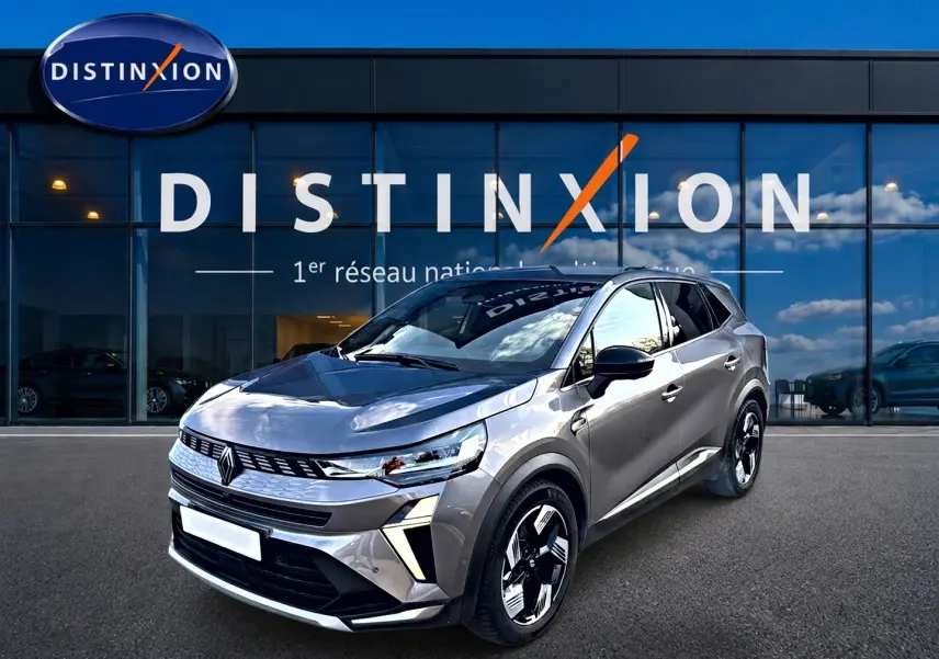Renault Symbioz gris 3/4 avant droit, SUV hybride avec calandre moderne et jantes bicolores distinctives.