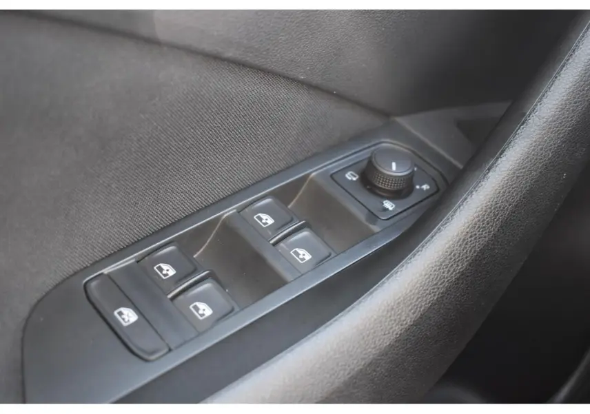 Gros plan sur les commandes de lève-vitres et réglage des rétroviseurs côté conducteur d'une Skoda Scala blanche.