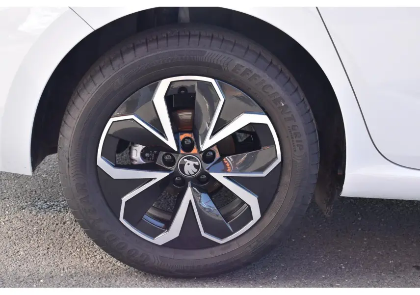 Gros plan sur la roue avant droite d'une Skoda Scala blanc glacier avec jante noire et argentée au design géométrique.