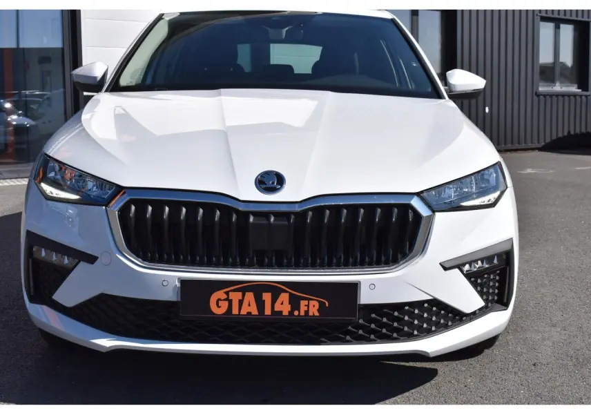 Vue frontale d'une Skoda Scala blanche Glacier avec calandre noire et phares LED anguleux sur parking.
