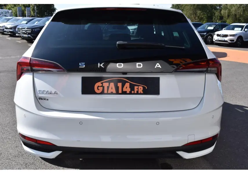 Vue arrière d'une Skoda Scala blanche glacier avec logo SKODA en lettres espacées sur la lunette arrière noire.