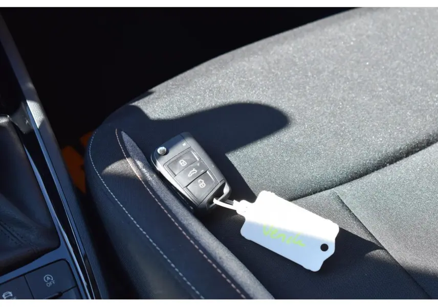Gros plan sur la clé noire posée sur le siège tissu noir à surpiqûres blanches, intérieur d’une Skoda Scala blanc glacier.