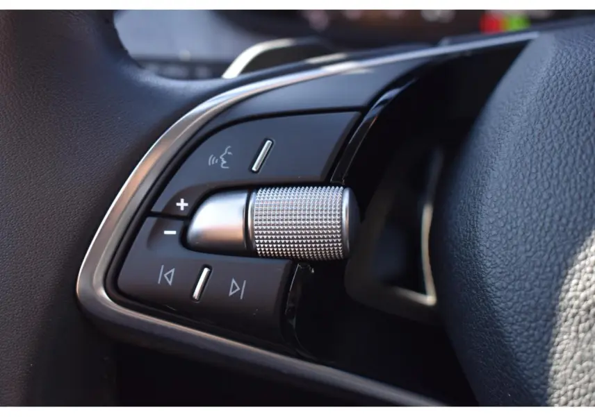 Gros plan sur les commandes multifonctions à gauche du volant cuir de la Skoda Scala 2025, finition noire et chrome.