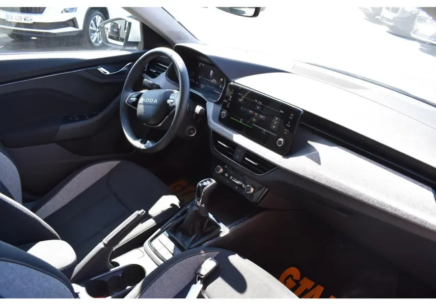Vue intérieure côté conducteur de la Skoda Scala 2025, avec tableau de bord gris suédine et sellerie tissu noir et gris.
