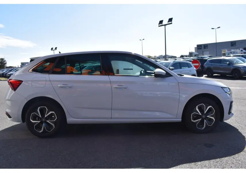 Vue de profil côté gauche d'une Skoda Scala blanc glacier garée en extérieur, avec jantes au design moderne.