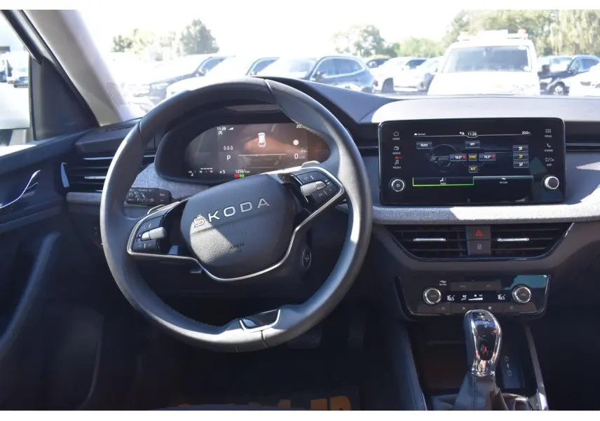 Vue intérieure centrée sur le volant Skoda et la planche de bord avec écran tactile et levier de vitesse.
