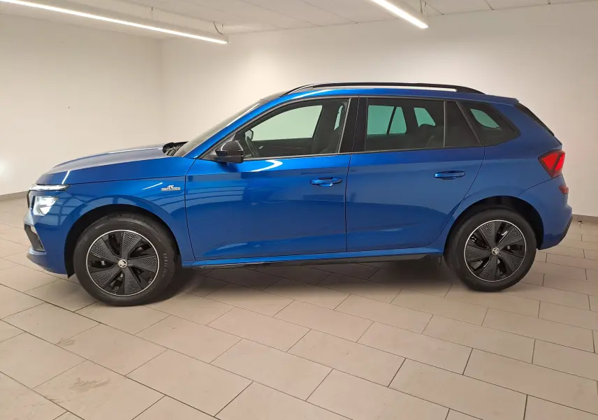 Vue de profil côté gauche d'un Skoda Kamiq 1.5 TSI 150 DSG7 Monte Carlo bleu RS avec jantes noires et toit ouvrant.