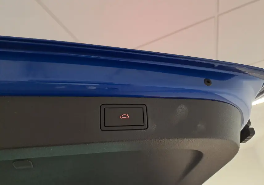Gros plan sur le bouton d'ouverture électrique du hayon du coffre bleu RS du Skoda Kamiq 2024 version Monte Carlo.