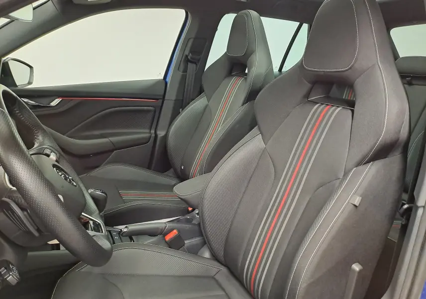 Vue intérieure côté conducteur du Skoda Kamiq 2024 bleu RS, sièges sport noirs avec bandes grises et rouges.